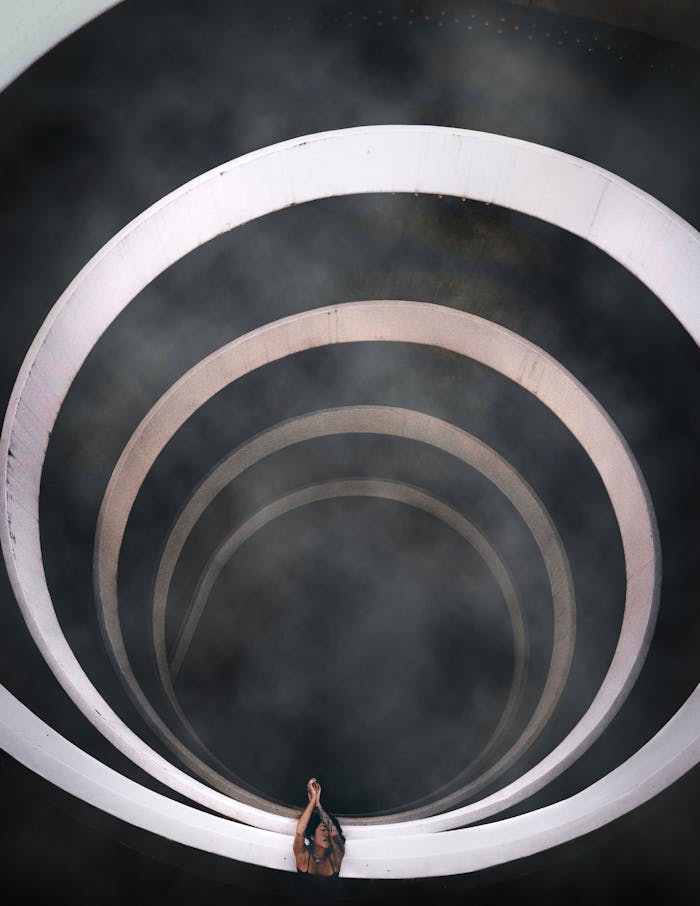 About A dramatic top-down view of a spiral staircase enveloped in smoke, showcasing modern architectural style.